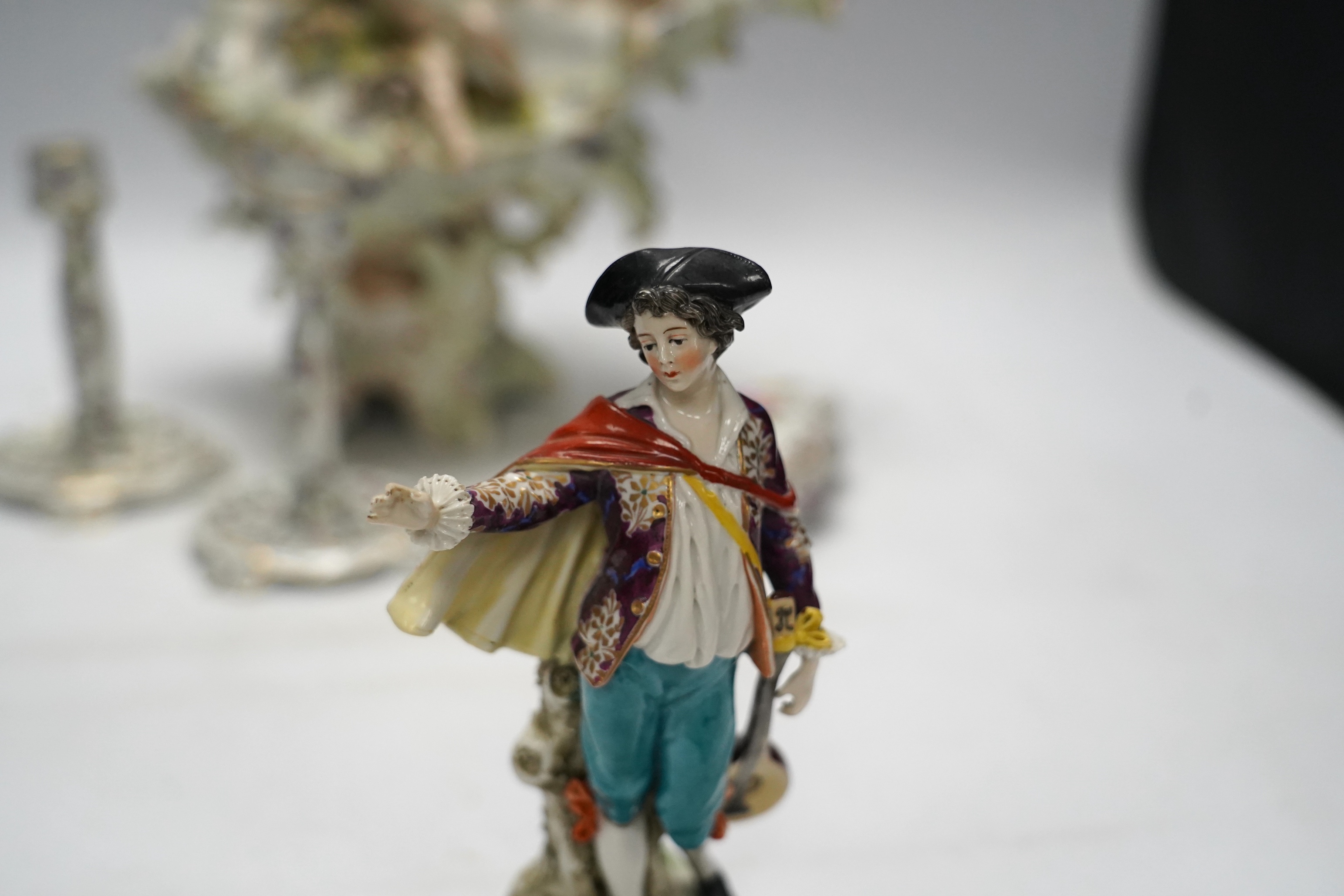 A porcelain shell-shaped centrepiece, a Dresden pill box, a pair of taper holders and a porcelain figure, tallest 21cm